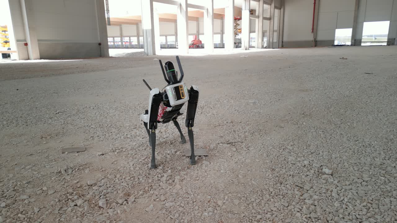 Robotic dog standing on gravel inside an industrial construction site under development