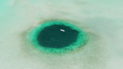 high aerial view of blue hole with fishing boat anchored, bahamas