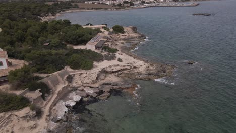 Aerial-drone-shot-flying-high-over-resort-along-rocky-highlands-beaches-in-Faro-de-s'Estalella,-Mallorca,-Balearic-Islands,-Spain-at-daytime