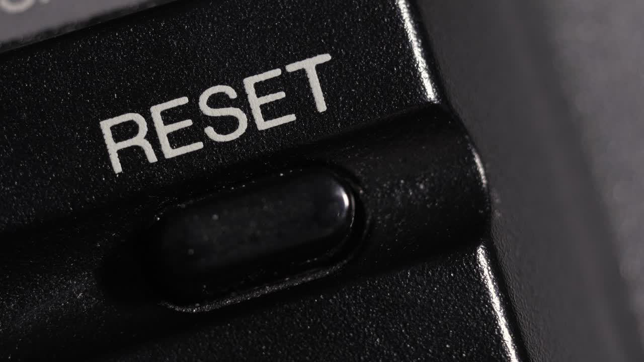 Diagonal macro close up of finger pressing black reset button symbolizing restart and renewal