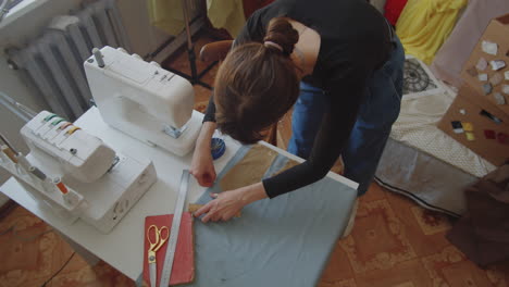 seamstress outlining sewing pattern on fabric with chalk