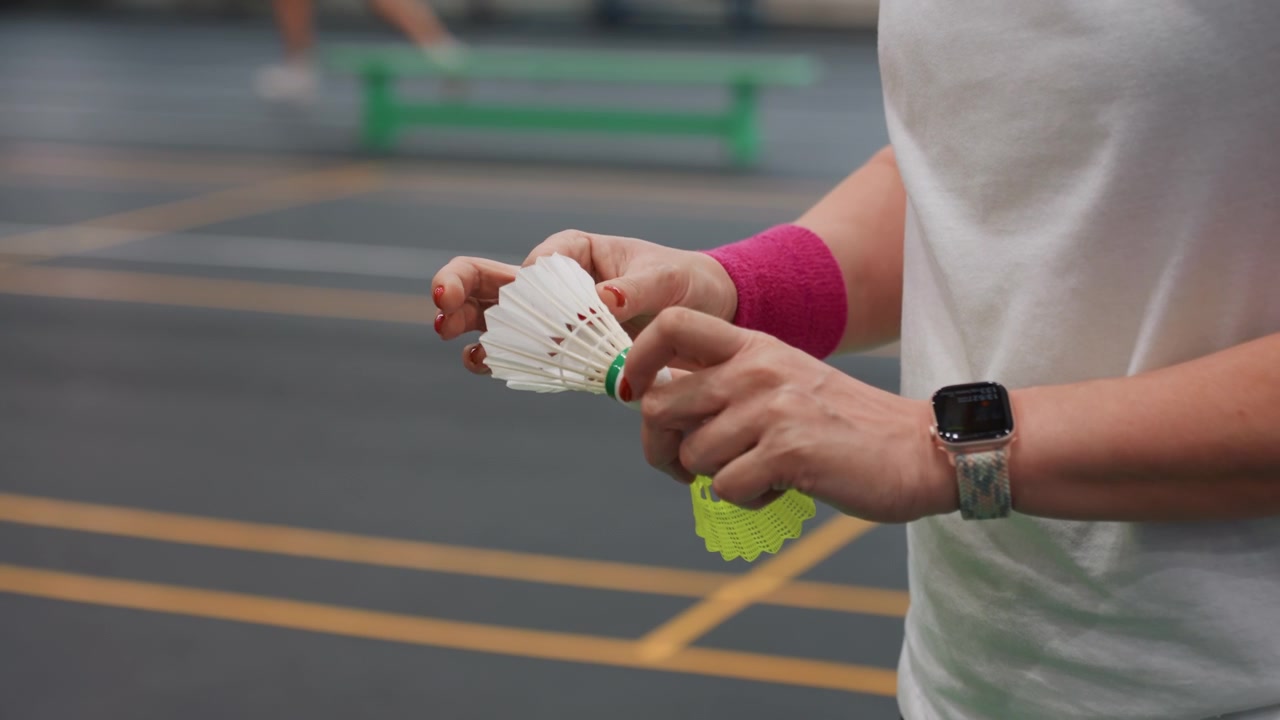 Mani femminili con volano in allenamento. Ragazze che si preparano per l'allenamento di badminton con volani e polsini. Atlete che eseguono routine di riscaldamento su campi al coperto prima delle sessioni di allenamento.