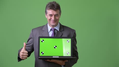 mature handsome businessman against green background