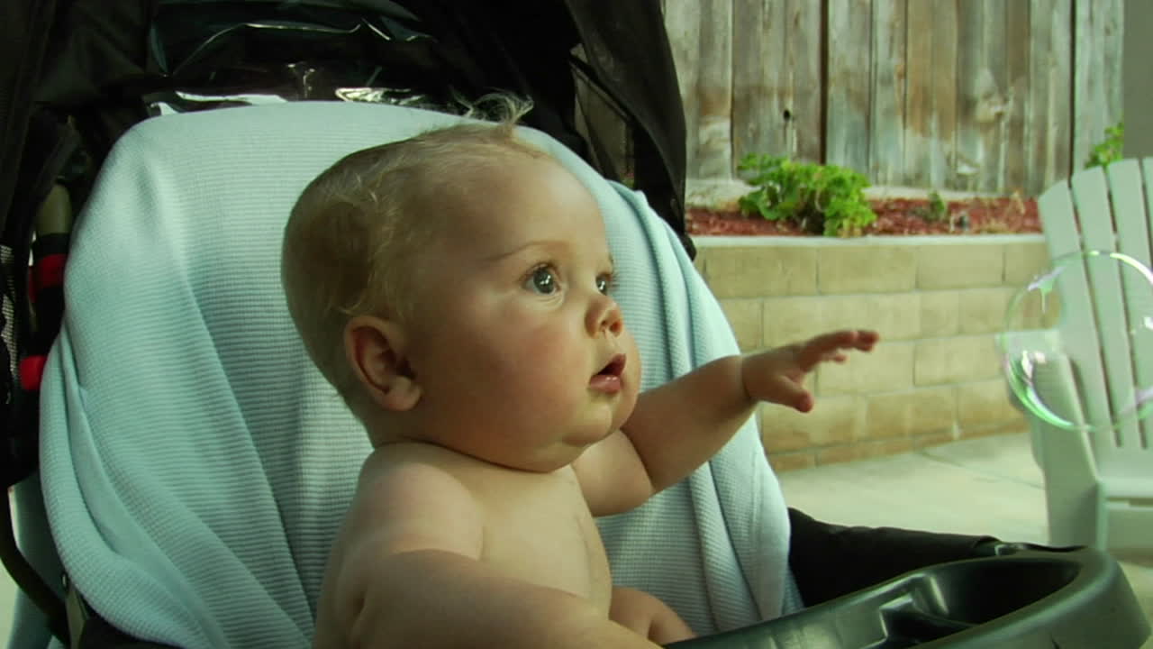 A baby pops a bubble in the air