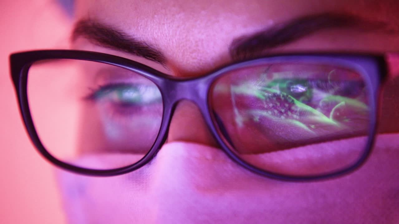 Close up of doctor with face mask watching Coronavirus statistics on laptop monitor reflected on glasses