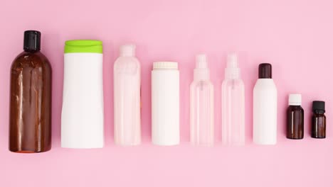 las botellas con productos cosméticos se mueven en tema rosa. detener el movimiento