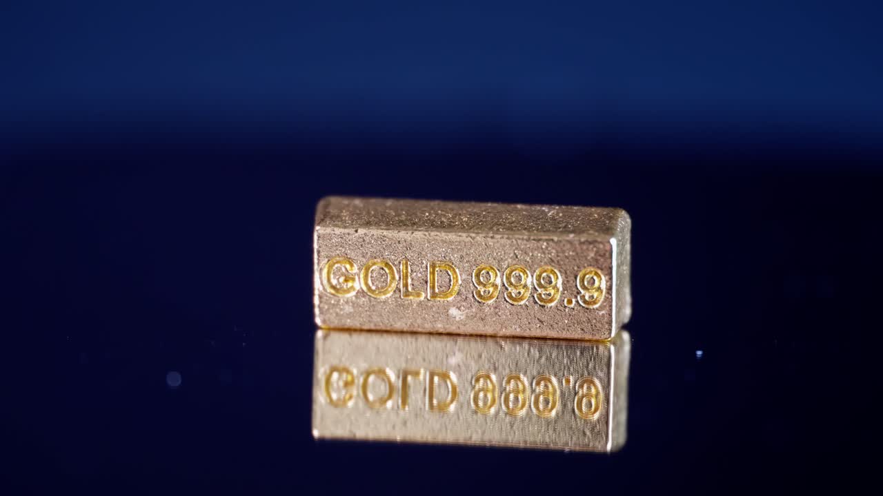 primer plano de una barra de oro de 999,9 girando en una superficie de espejo, con sorprendentes reflejos que simbolizan la riqueza y el lujo