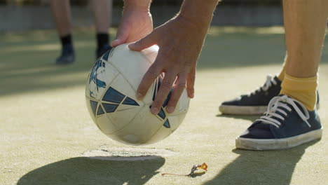 primo piano di uno sportivo irriconoscibile che mette il pallone da calcio a terra e lo calcia