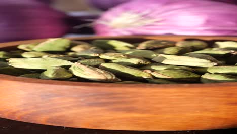 close-up of green cardamom pods in a wooden bowl