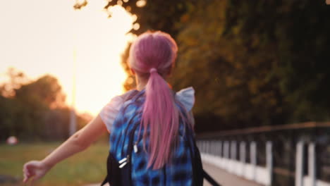 cheerful child with a satchel behind his back runs towards the camera back to school shallow depth o