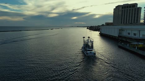 aerial view of commercial fishing boat heading out to work in biloxi, mississippi at sunset