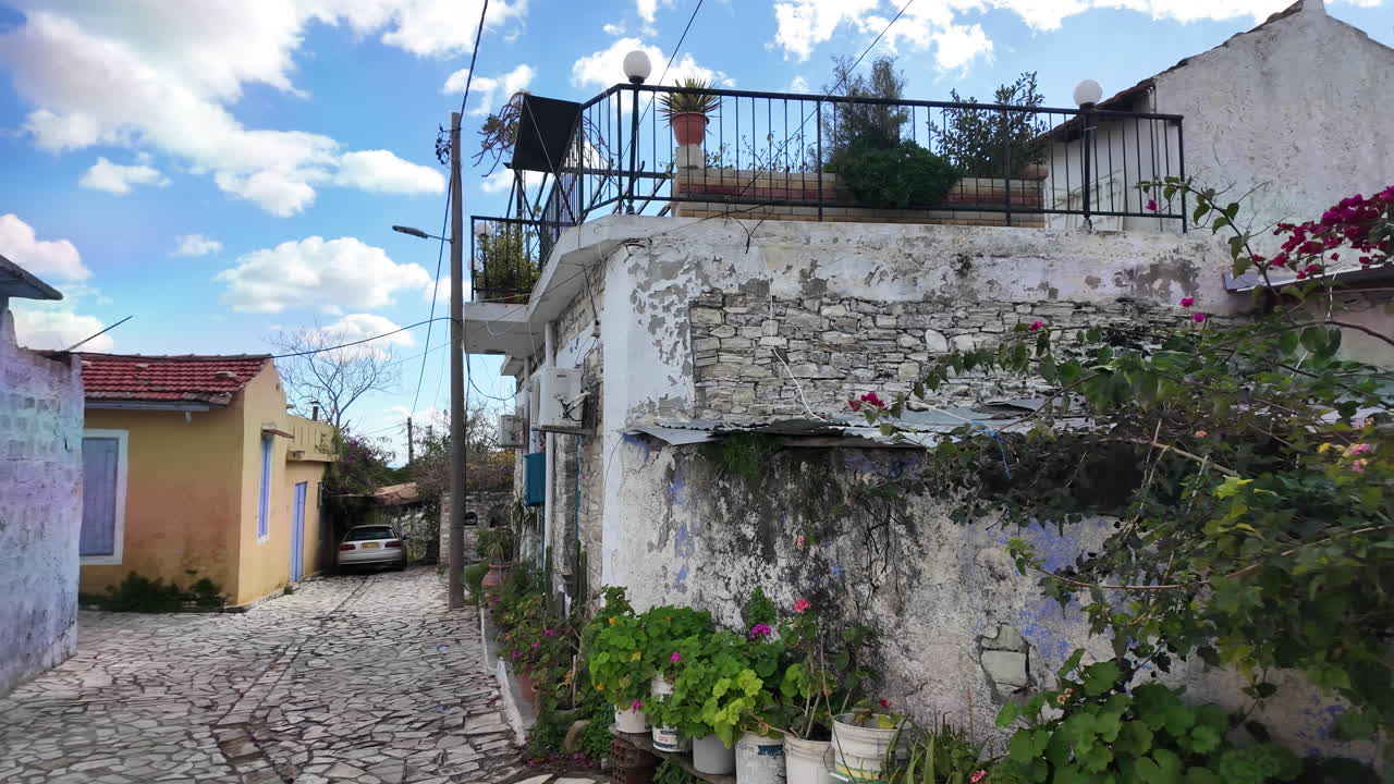 Charming narrow street in Lefkara with stone houses, potted plants, and a red car