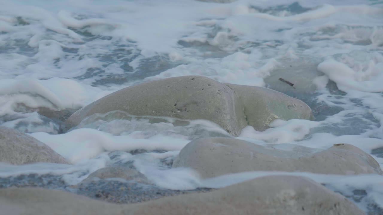 4K Cinematic slow motion shot of waves hitting rocks on the beach during sunset, at Church Ope, on Portland, Dorset.
