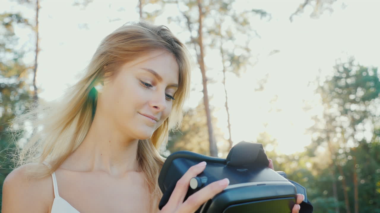 가상 현실에 뛰어들려면 한 젊은 여성이 태양 아래에서 가상 현실의 헬멧을 씁니다.