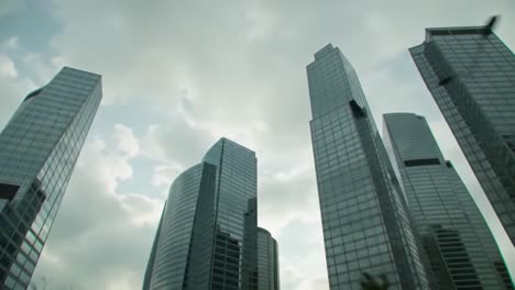 tall glass skyscrapers dominate the skyline as clouds swirl above. the setting captures the vibrant energy of a city, showcasing architectural brilliance during daylight hours.