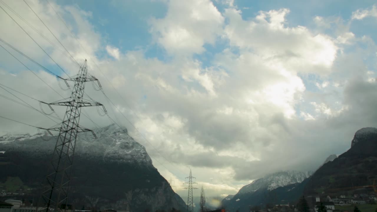 Snowy Mountains and Power Lines under a Cloudy Sky
