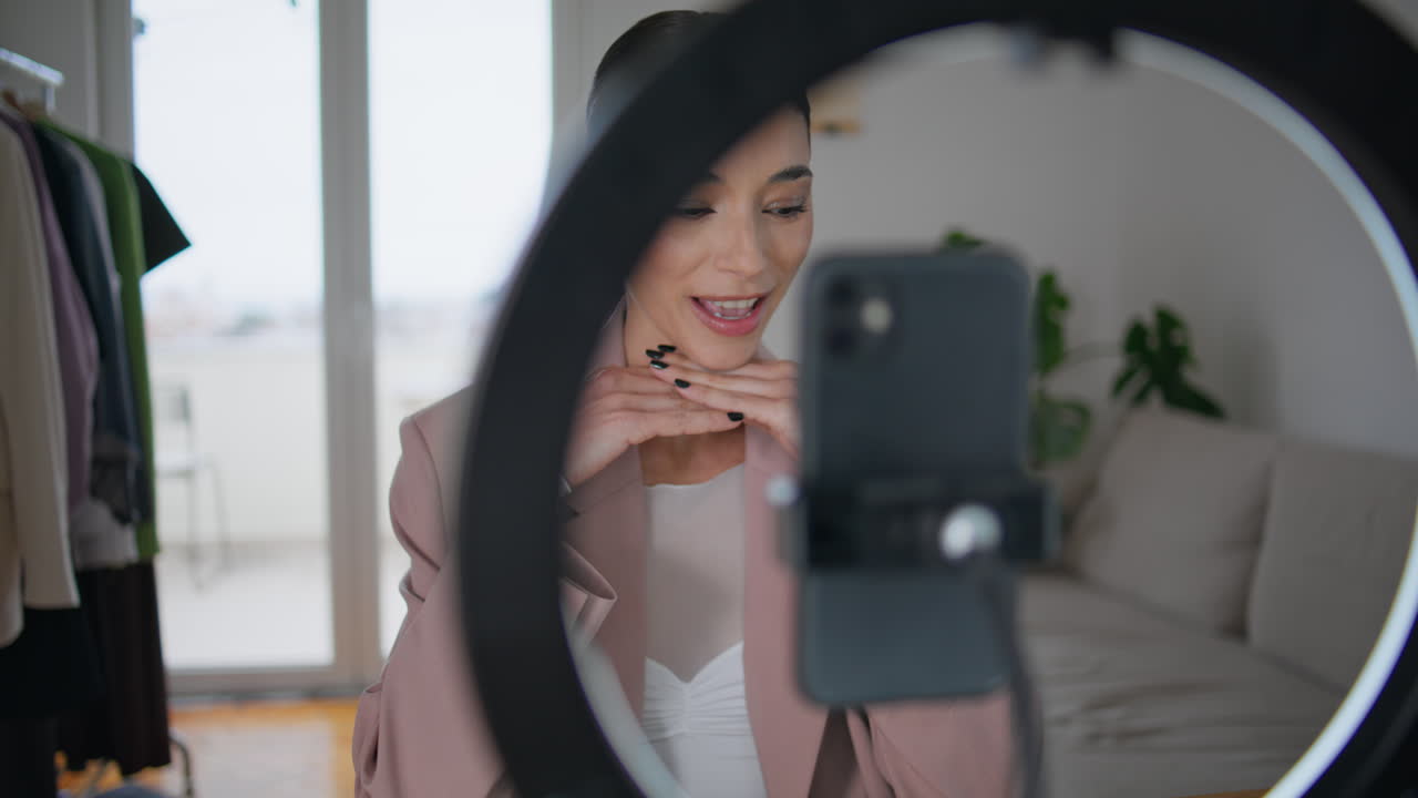 blogger mujer ajustando el teléfono inteligente en el trípode en la habitación. influencer grabando video