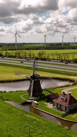 dutch windmill and canal landscape with highway and wind turbine