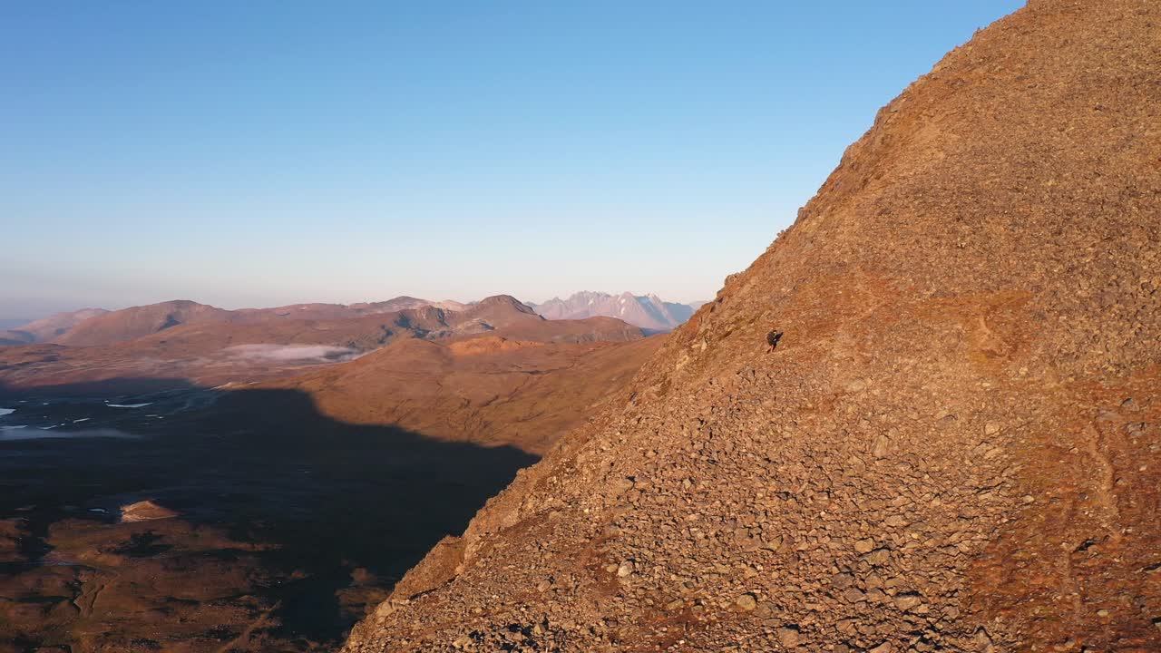 excursionista escalando una montaña al atardecer en el ártico noruego