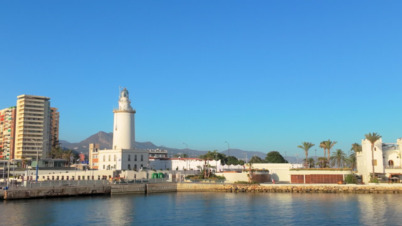 Malaga - Lighthouse by the marina with mountains and modern buildings under a clear blue sky