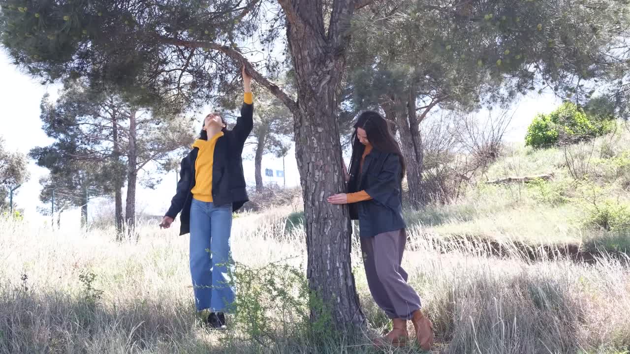 Two women in a field by a tree