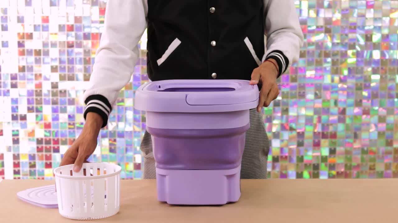 Person demonstrating how to use a compact, portable folding washing machine for small laundry loads