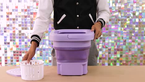 person demonstrating how to use a compact, portable folding washing machine for small laundry loads