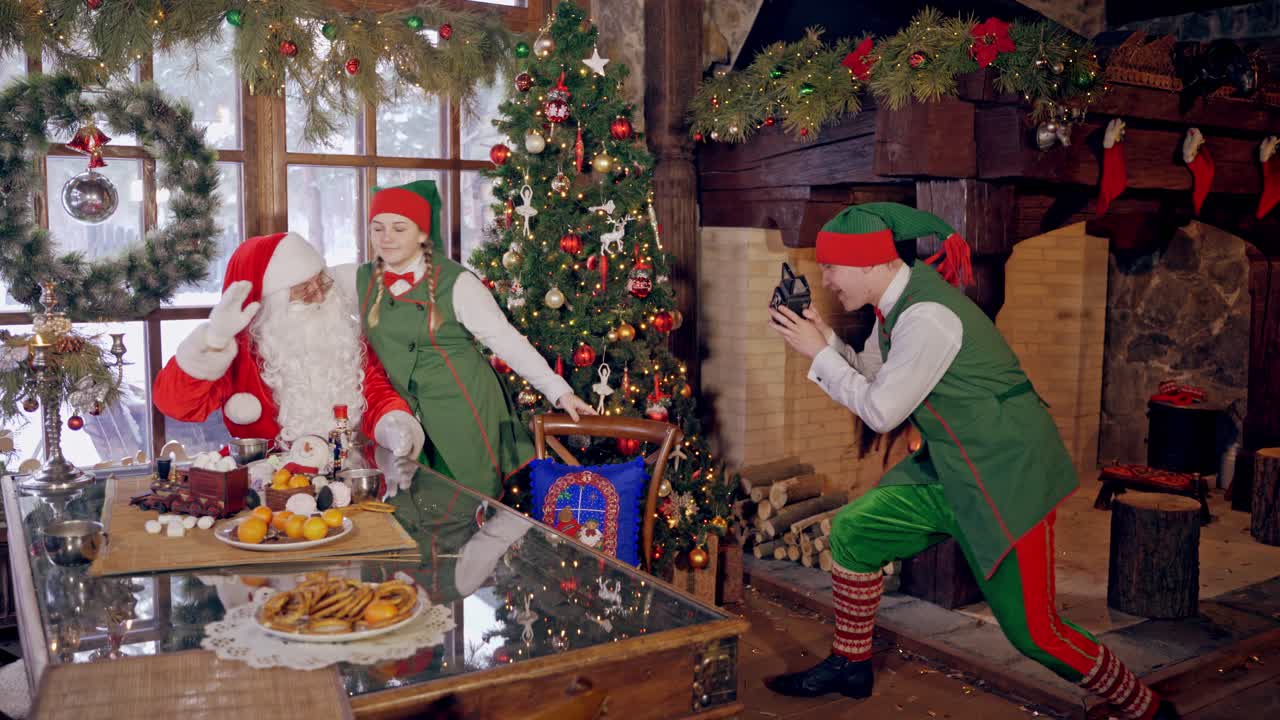 Santa Claus making photos. Santa Claus photographing in red traditional outfit with elves