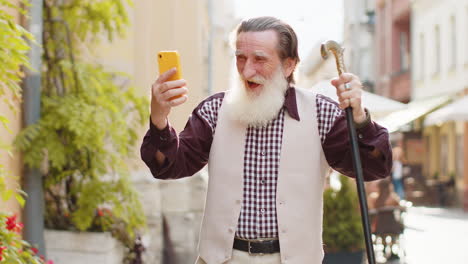 senior man use mobile smartphone celebrating win good message news outdoors in urban city street