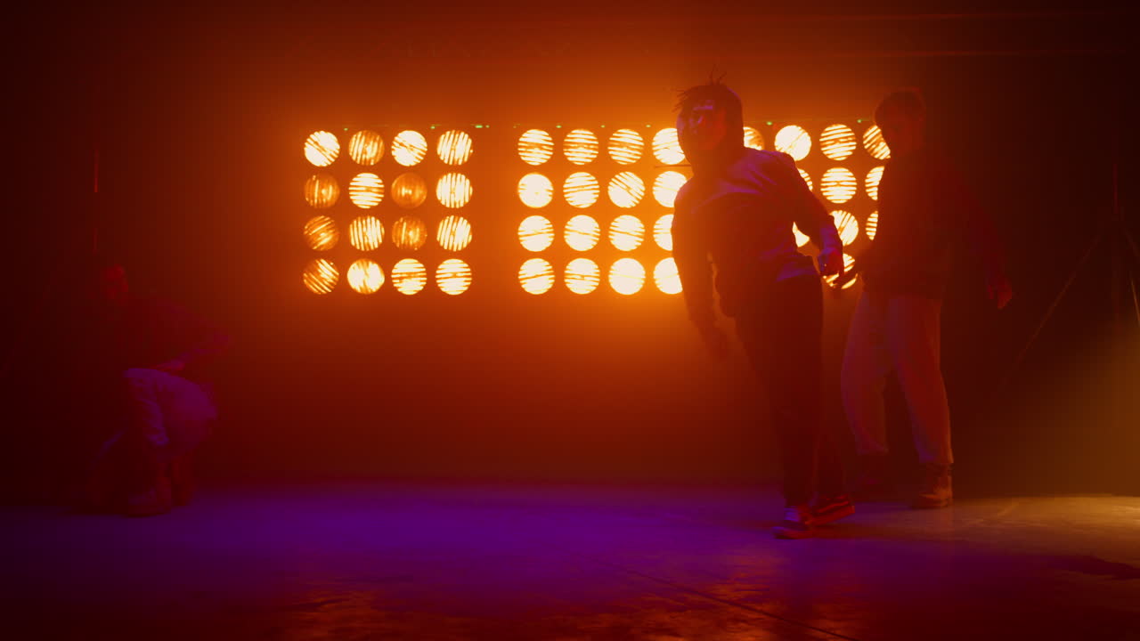 un equipo de breakdance haciendo trucos en la pista de baile, siluetas de un equipo de hip hop en el escenario.