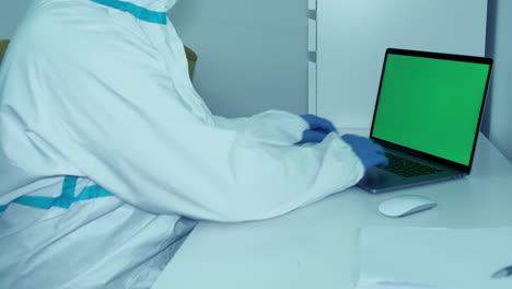 Slow-pan-hospital-worker-typing-research-on-computer-in-covid-19-protective-gown-and-gloves