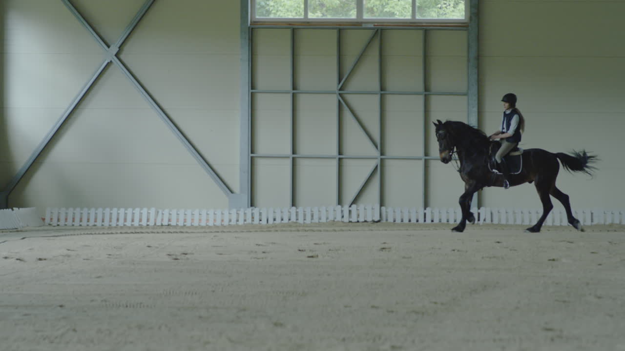A person riding a horse in an indoor equestrian arena
