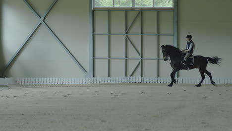 a person riding a horse in an indoor equestrian arena