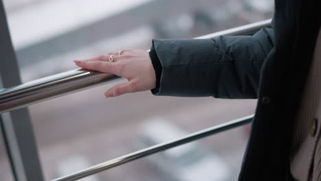 close-up of woman hand gliding gently on sleek iron rail, with blurred background of mall glass reflecting outdoor environment and soft lighting creating calm and minimalist ambiance