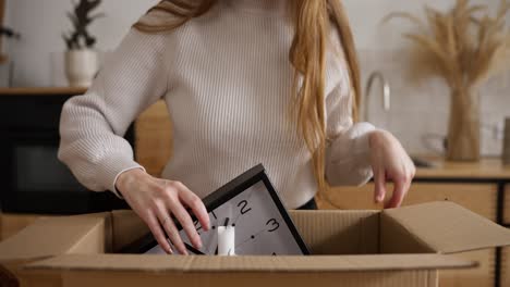 woman packing clock into moving box