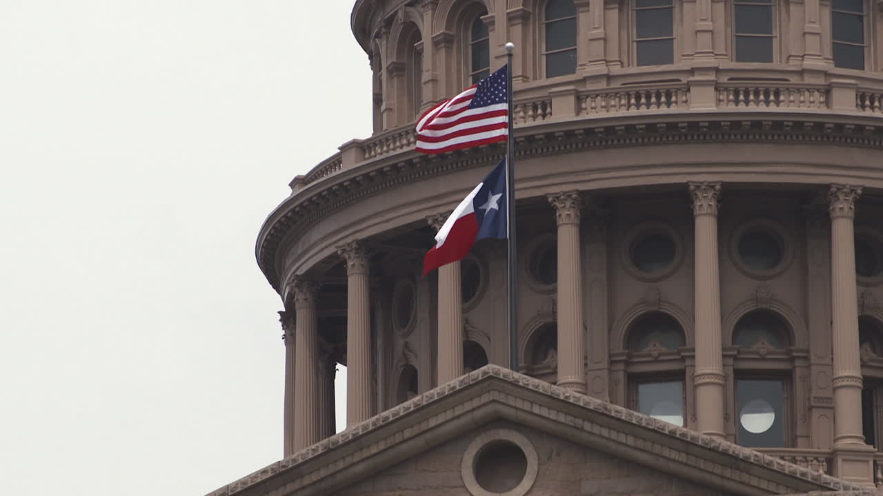 Close-Up Of U.S. And Texas Flags Waving Above Texas State Capitol In Austin, Texas