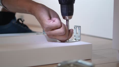 a man using a screwdriver to assemble furniture