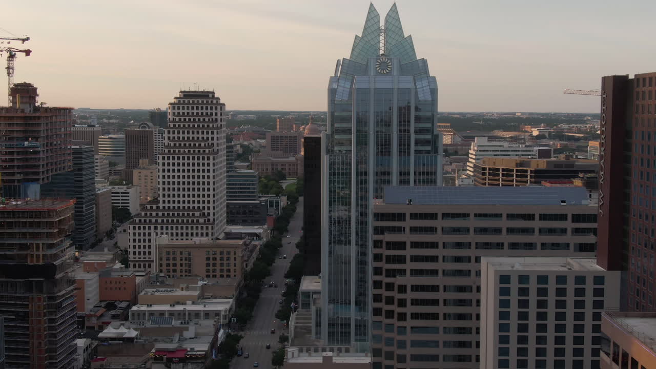 Panoramica aerea di Congress Avenue nel centro di Austin, Texas, con edifici in primo piano e il Campidoglio sullo sfondo al tramonto.