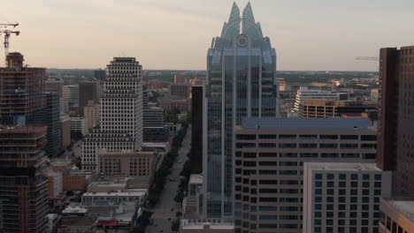 aerial pan across congress avenue in downtown austin, texas with buildings in foreground and capitol building in background at sunset.