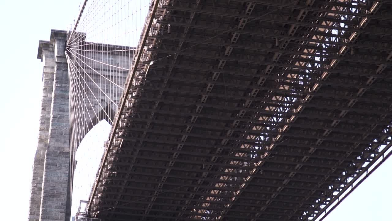 Iconic Brooklyn Bridge extreme close up starting from underneath the Brooklyn Bridge tilting up in slow motion from the sightseeing sailing boat.