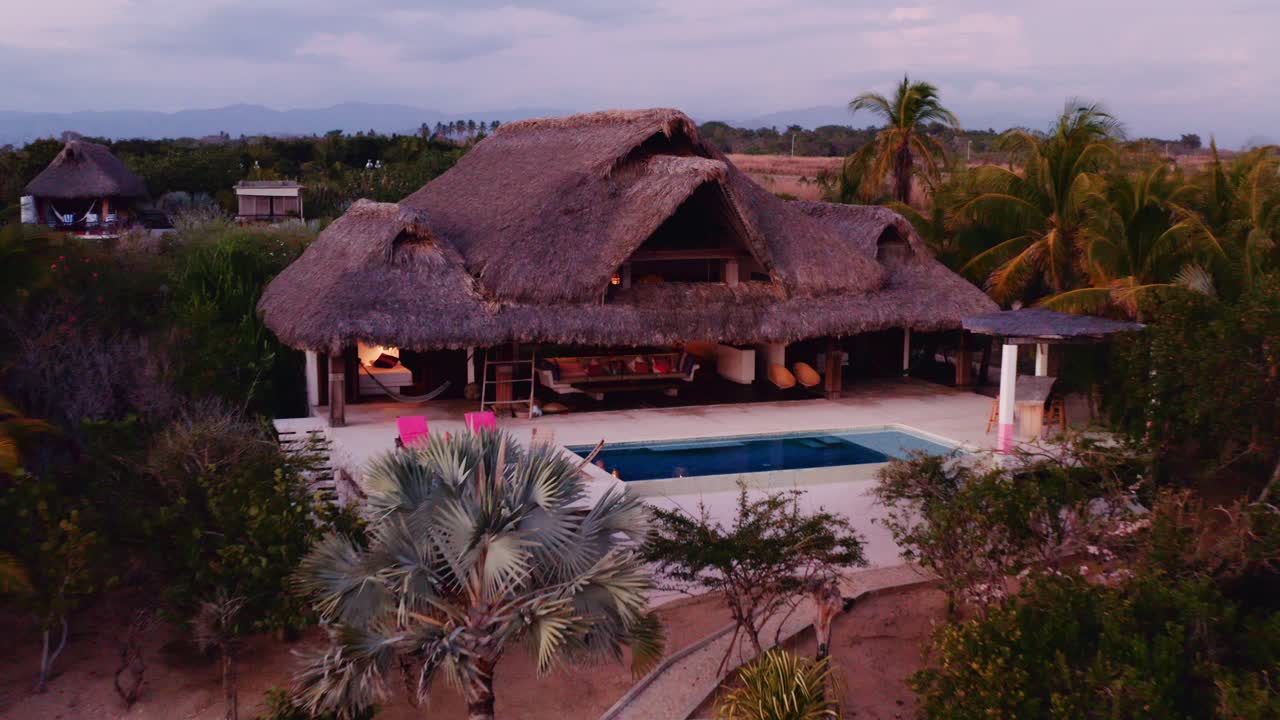 drone disparó lentamente y reveló villa de lujo con palapa y gran piscina al atardecer en oaxaca méxico