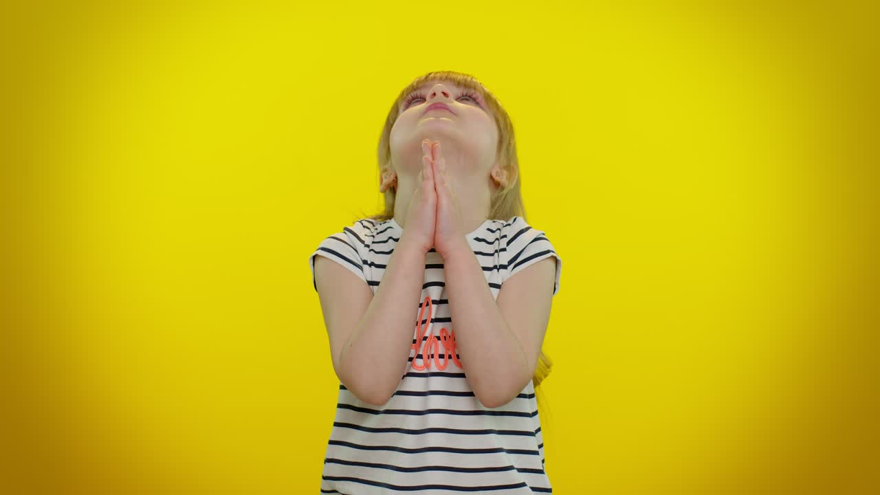 Child girl sincerely praying to God and looking up with pleading expression, begging apology, help