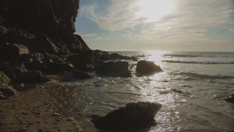 Wasser-Ergießt-Sich-über-Felsen,-Während-Die-Flut-Bei-Sonnenuntergang-In-Den-Strand-Von-Chapel-Porth-Rollt,-Breit