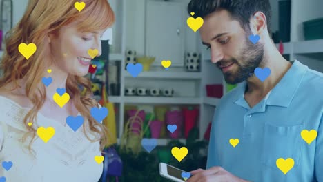 animación de corazones azules y amarillos sobre diversas personas que pagan con su teléfono inteligente