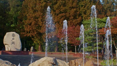 A-beautiful-wide-angle-view-of-Asian-south-Korean-park-with-fountains,-trees-and-leaves-in-the-fall-and-autumn-season-at-daytime-with-sunlight