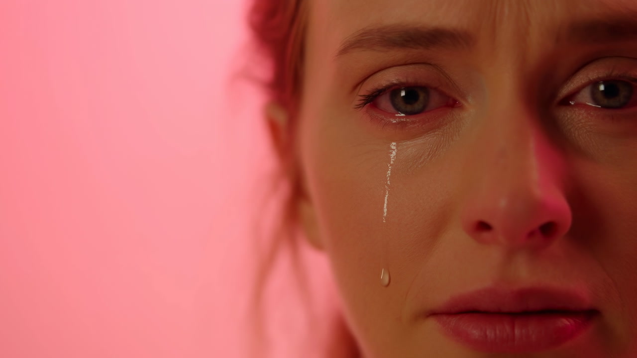 Caucasian Woman Crying Close Up Pink Background, Single Tear Rolling Down Cheek, Somber Expression, Intimate