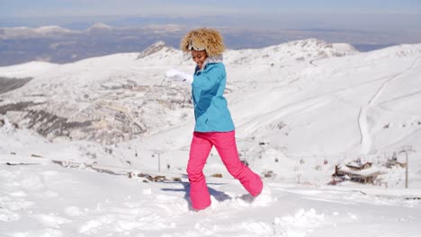 una mujer linda con ropa de esquí pateando nieve.