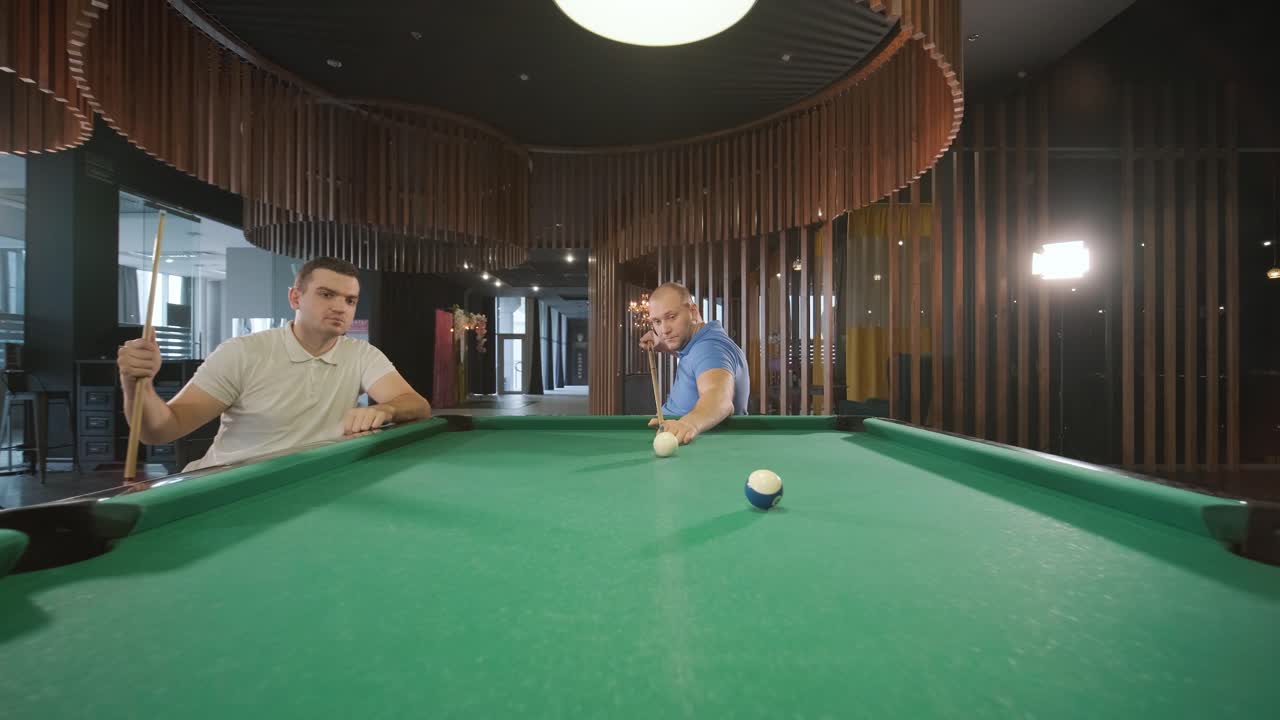 Adult men with disabilities in a wheelchair play billiards in the club