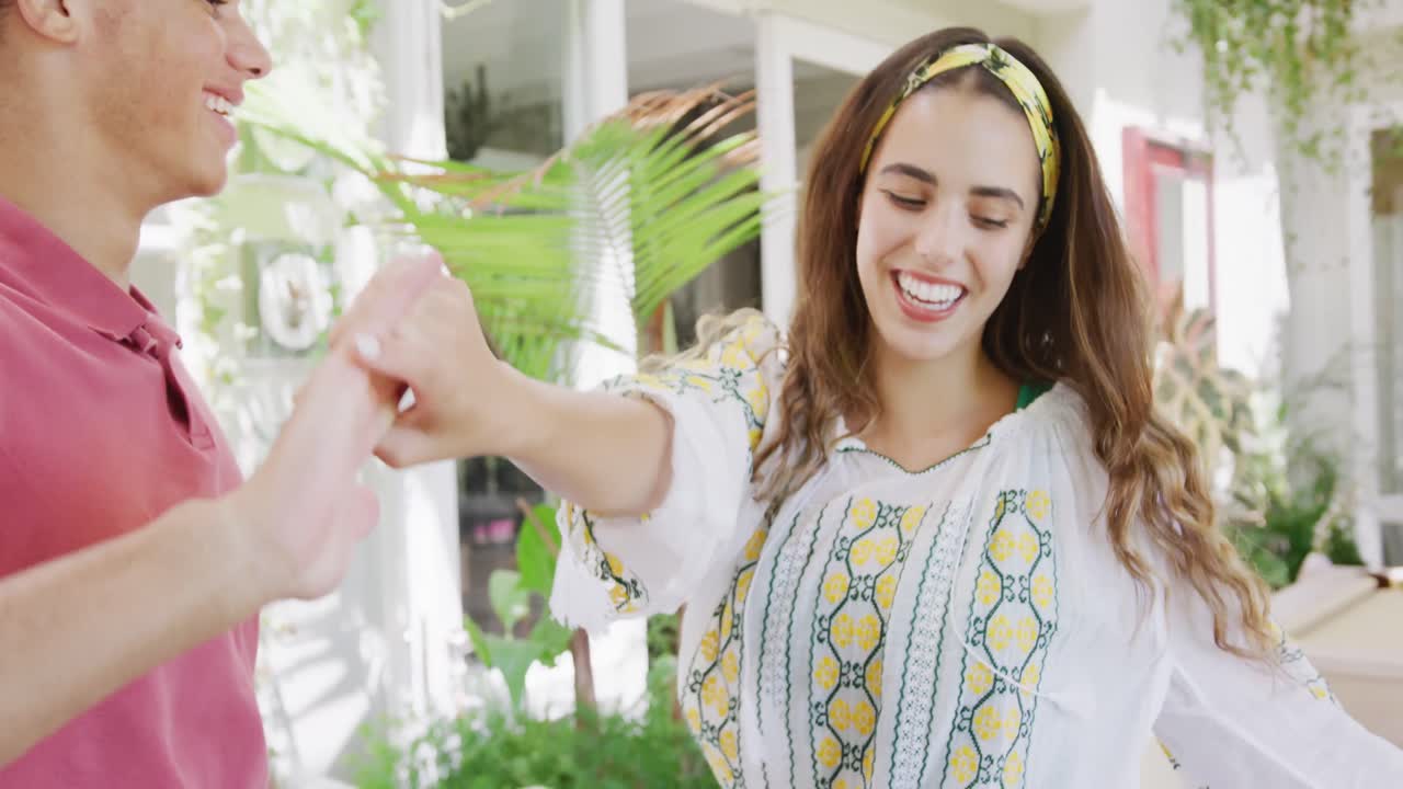 retrato de una feliz pareja biracial pasando el tiempo en casa tomados de la mano y bailando