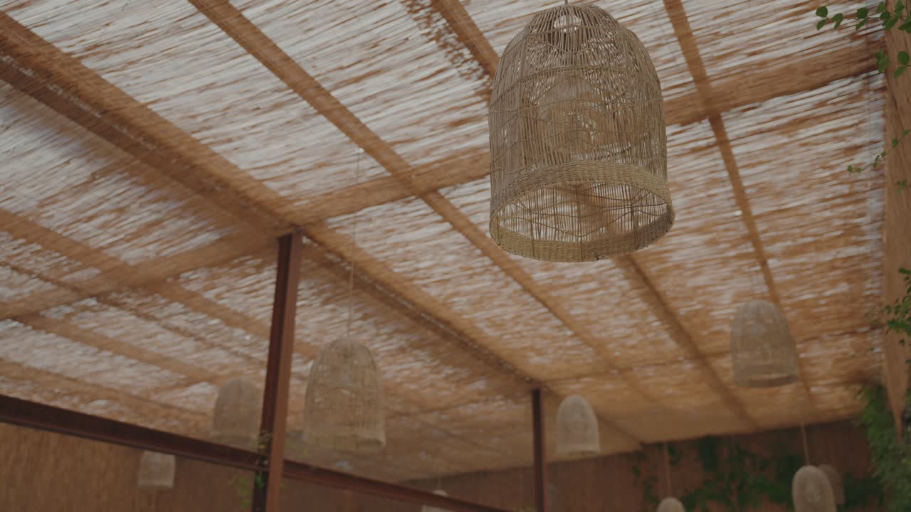 Decorative wicker lanterns suspended beneath natural pergola roof